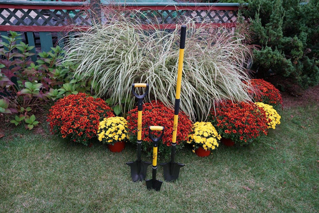 The three Spear Head Spade garden tools displayed among flowers