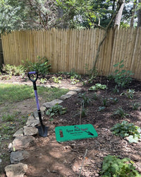 Spear Head Spade lavender D-handle spade in a mulched garden bed with the foam garden kneeler laid on the ground beside it