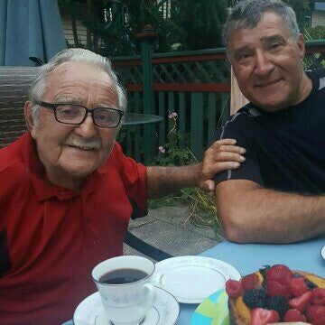Daniel Mathieu, in a red shirt, with his son Julien at an outdoor table
