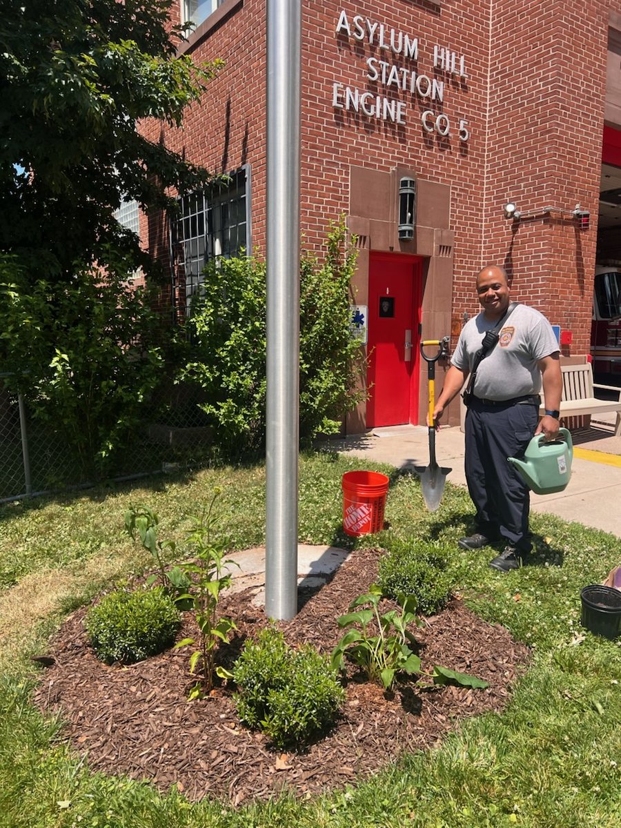 Hartford firefighter with a Spear Head Spade planting shrubs around the station flagpole