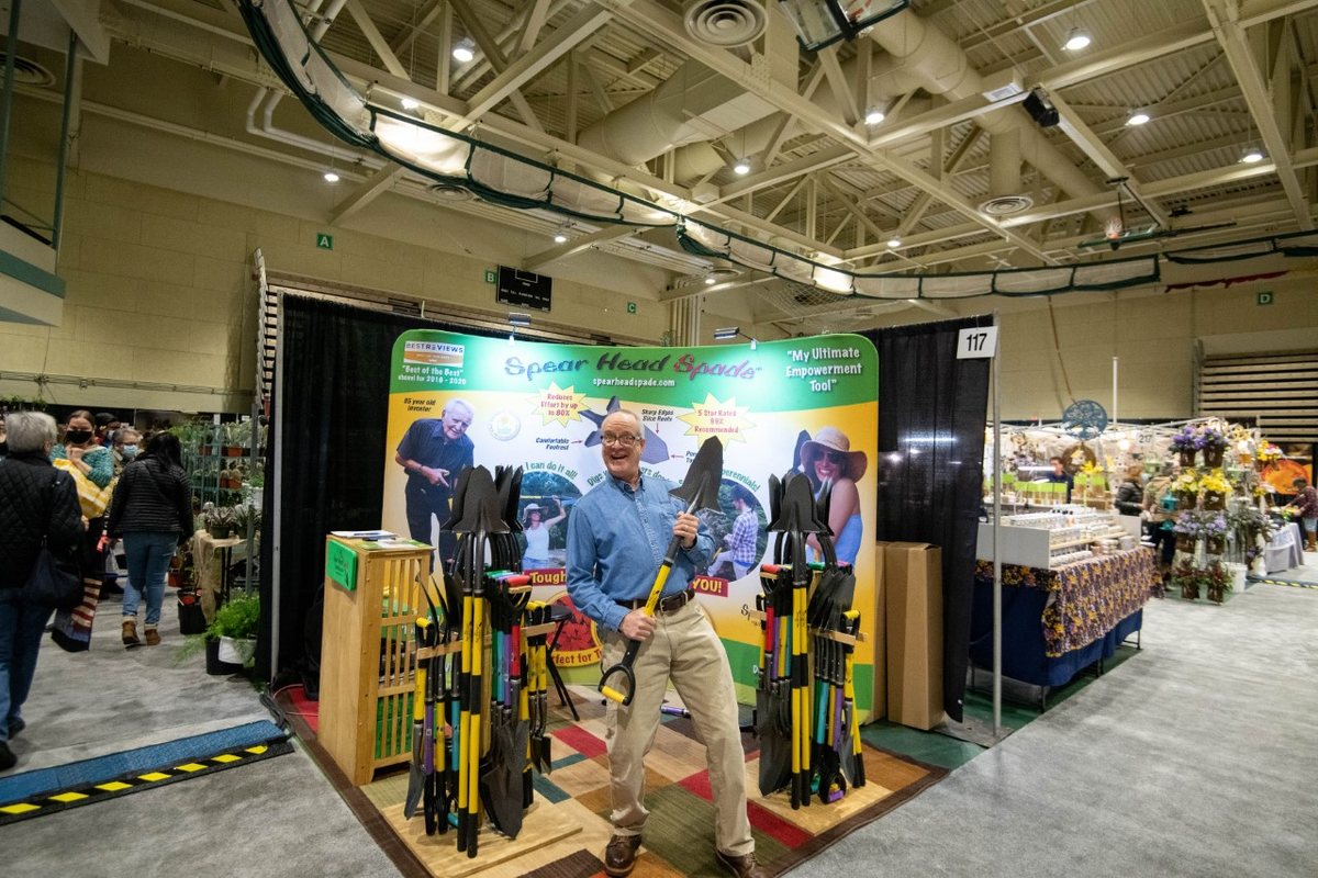 Hugh standing at the Spear Head Spade booth with display racks of spades at the Capital Region Garden Expo