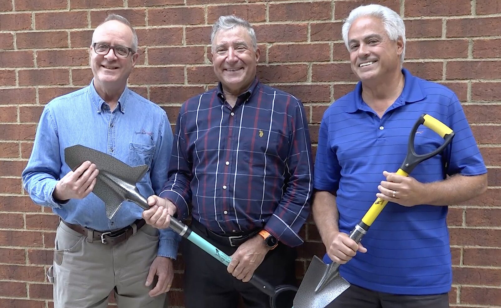 Hugh Mura, Julien Mathieu, and Harry Freeman holding Spear Head Spades in front of a brick wall, August 2025